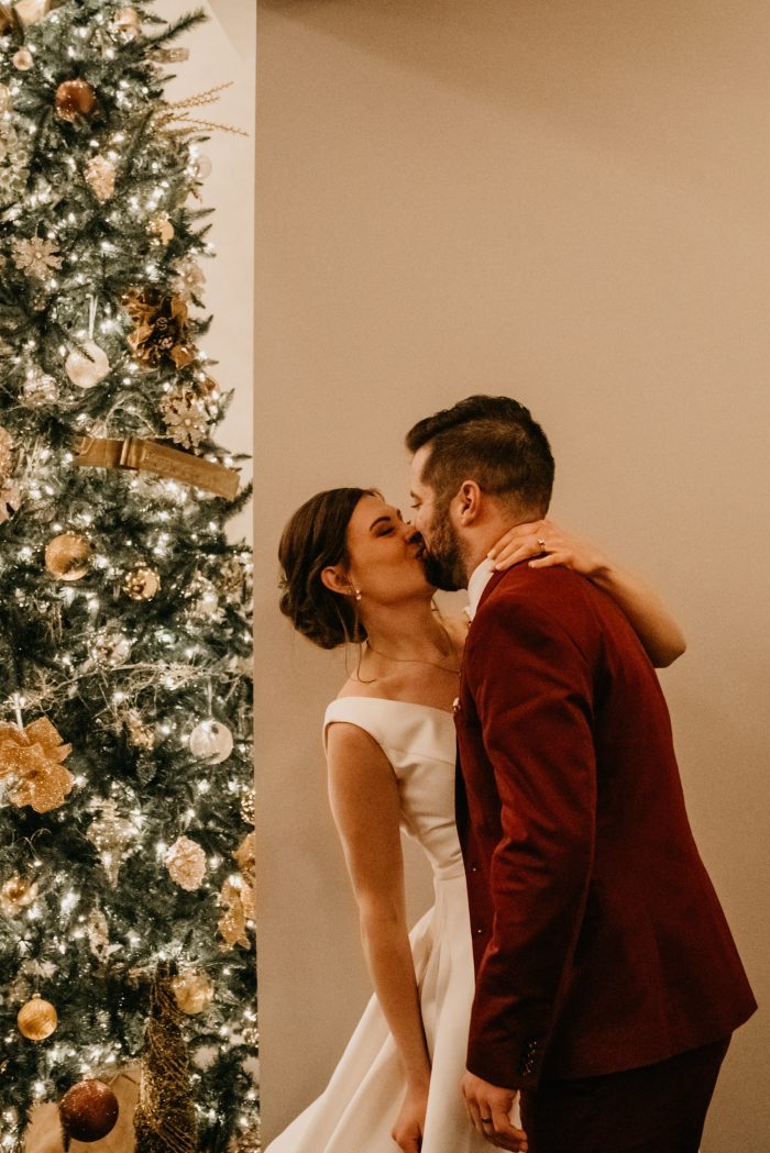 Bride and Groom kissing in front of glowing holiday tree