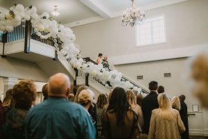 Bride and Dad walking down a Grand Staircase covered in balloons