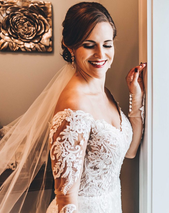 Bride looking over her shoulder standing in front of a brides room window
