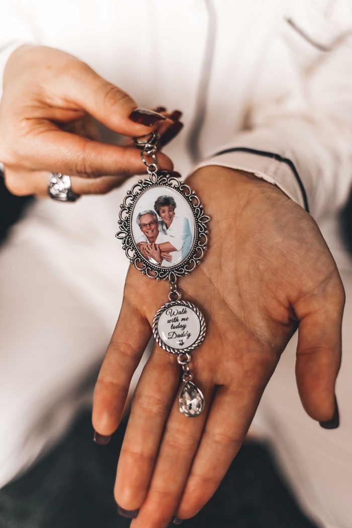 Bride holding a vintage photo keychain with a photo of her parents